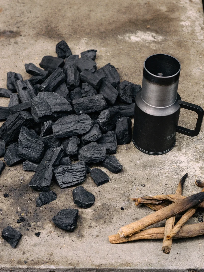 Węgiel drzewny, komin rozpałkowy i drewniana rozpałka na betonowej płycie